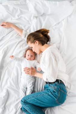 Bebekle yatakta yatan kot pantolonlu annenin üst görünümü