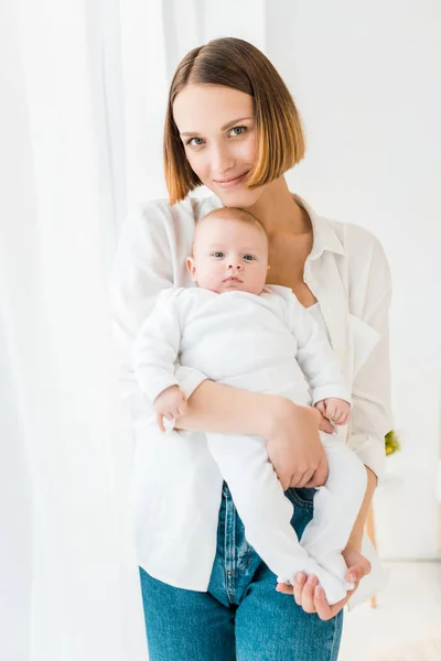 Sonriente Joven Madre Camisa Blanca Sosteniendo Bebé Casa — Foto de Stock