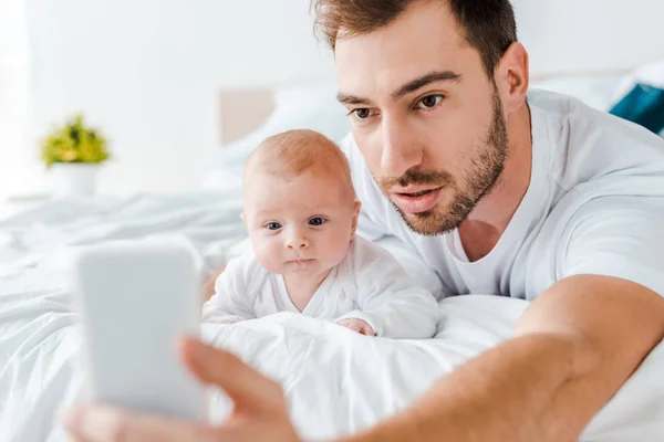 Μούσι Μπαμπάς Λήψη Selfie Μωρό Στο Κρεβάτι — Φωτογραφία Αρχείου