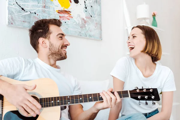 Sorrindo Homem Sentado Cama Com Esposa Tocando Guitarra — Fotografia de Stock