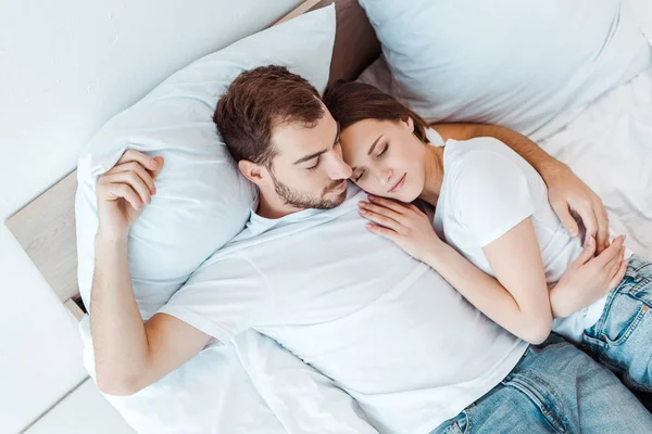 yatakta uyurken karısını kucaklayan adamın havai görünümü