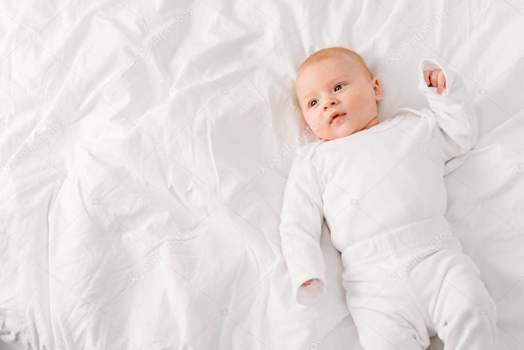 Top view of infant baby lying on white sheet