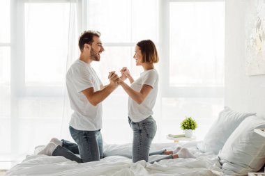 Mutlu çift el ele tutuşuyor ve yatak odasında birbirlerine bakıyor