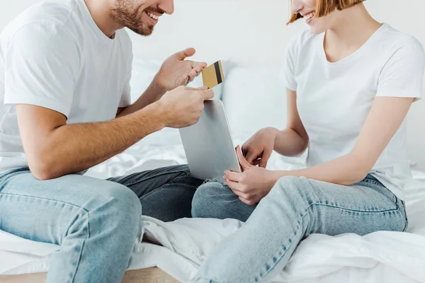 Visão Parcial Casal Sorridente Com Cartão Crédito Laptop Sentado Cama — Fotografia de Stock