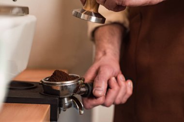 Cropped view of barista in brown apron preparing coffee clipart