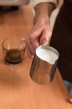 Çelik süt sürahi tutan barista kırpılmış görünümü