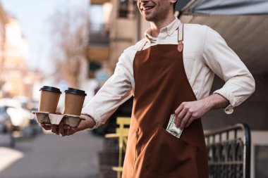 Barista kahve kağıt bardak tutan ve cebine para koyarak kırpılmış görünümü