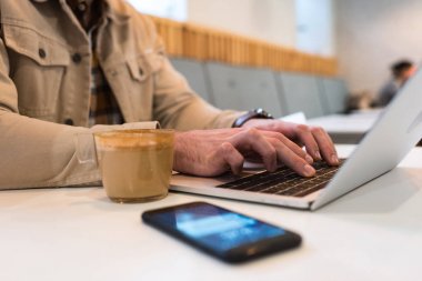 Dizüstü bilgisayar klavyesi üzerinde kahve yazarak fincan ile freelancer Kırpılmış görünümü