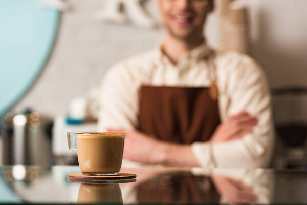 Selective focus of barista and cup of coffee on foreground