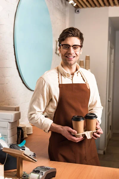 微笑的咖啡师在眼镜拿着带咖啡的外带杯托架 — 图库照片