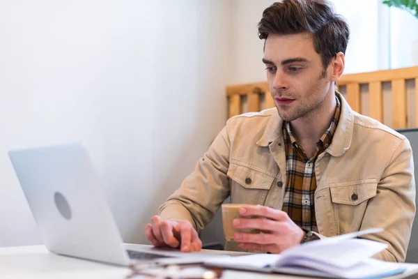 Freelancer Concentrado Sosteniendo Taza Café Usando Laptop — Foto de Stock