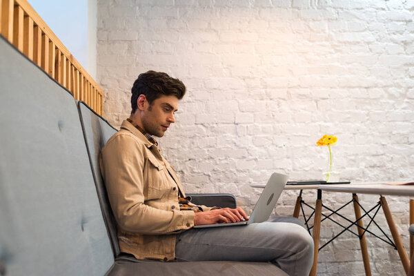 Freelancer in jacket and jeans working with laptop in cafe