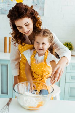 heyecanlı kızı ile mutlu anne mutfakta yumurta ve un ile kase yakınında birlikte ayakta