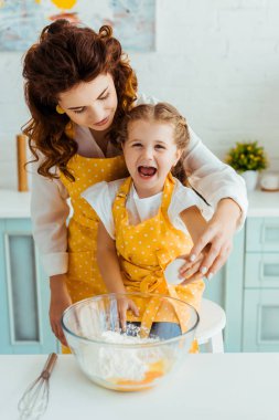 anne ve heyecanlı kızı mutfakta un ile kase içine birlikte yumurta parçalama