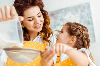 gülümseyen anne ve kızının birlikte un eleyen seçici odak