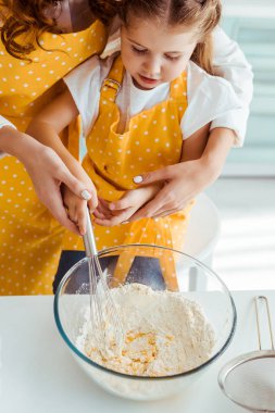 anne ve kızı apronlar içinde balon çırpma kase ile un ve yumurta karıştırma