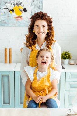 mutlu anne ve polka nokta sarı önlük mutfakta gülen kızı