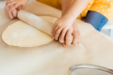 anne ve kızı pişirme parşömen kağıt üzerinde ahşap oklava ile hamur haddeleme kırpılmış görünümü