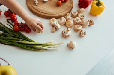 sebze ile masada mantar tutan çocuk kısmi görünümü