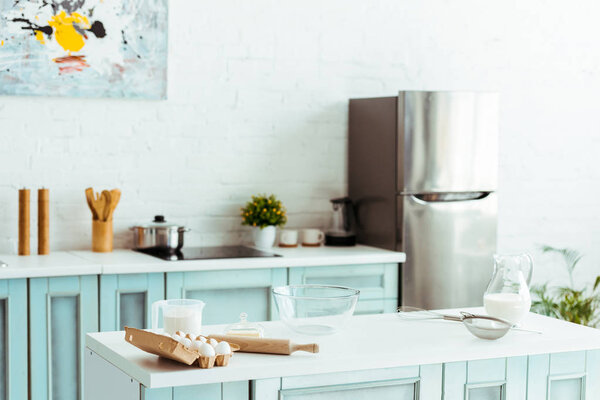 современная светлая кухня с хлебобулочными ингредиентами и кухонной утварью на столе
