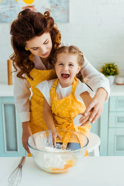 母亲和兴奋的女儿粉碎鸡蛋一起到碗与面粉在厨房 — 图库照片