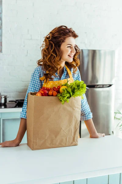 Uśmiechnięta Kobieta Stoi Pobliżu Worek Papierowy Dojrzałych Owoców Warzyw Kuchni — Zdjęcie stockowe