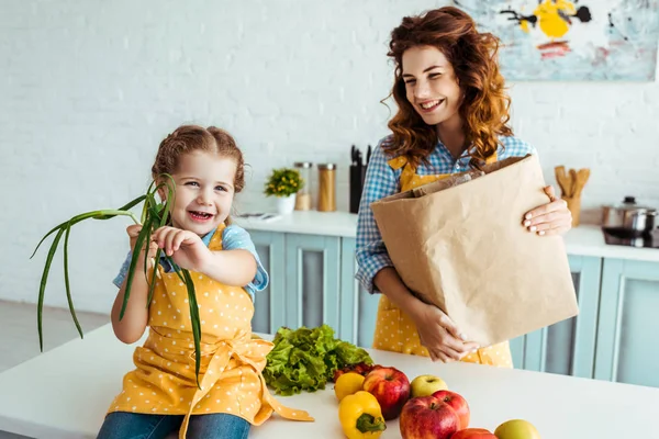 Lycklig Mamma Med Papperskasse Tittar Upphetsad Dotter Innehar Grön Lök — Stockfoto