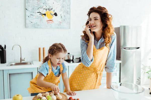 Mãe Feliz Falando Smartphone Enquanto Filha Colocando Cogumelos Tábua Cortar — Fotografia de Stock