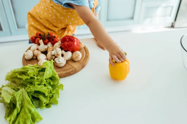 Vista Recortada Del Niño Delantal Lunares Sosteniendo Pimiento Amarillo Mesa — Foto de Stock