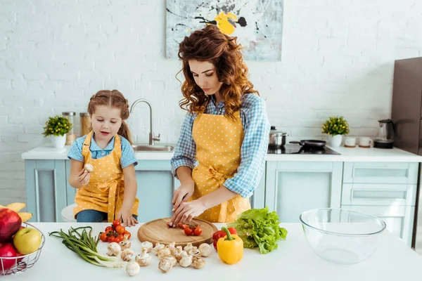 Μητέρα Πουά Ποδιά Κοπή Ωμά Λαχανικά Κοντά Κόρη Στην Κουζίνα — Φωτογραφία Αρχείου