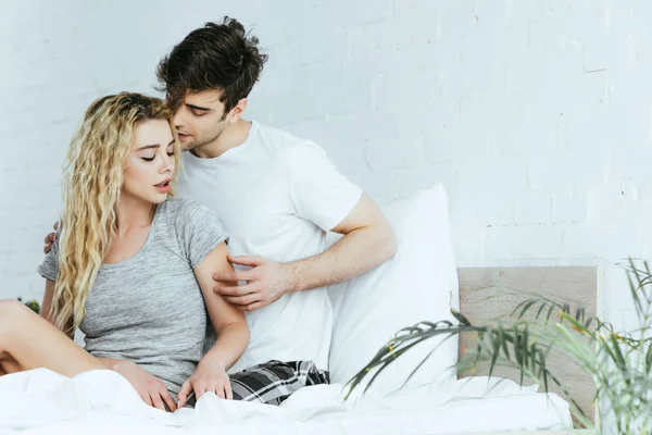 Handsome Man Touching Blonde Girlfriend Sitting Bed — Stock Photo, Image