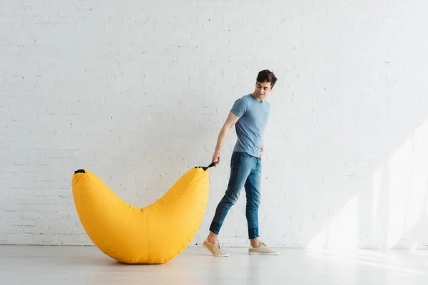 Happy Handsome Man Holding Yellow Bean Bag Chair While Standing — Stock Photo, Image