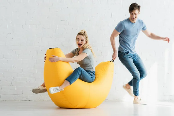 Handsome Man Pulling Yellow Bean Bag Chair Cheerful Woman — Stock Photo, Image