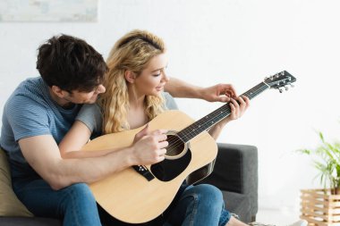 yakışıklı adam evde akustik gitar çalan sarışın mutlu kadın öğretim 