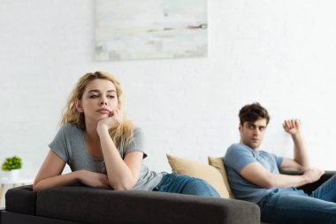kavga dan sonra erkek yakın kanepede oturan üzgün sarışın kadın seçici odak 