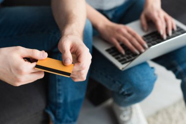 dizüstü bilgisayar kullanarak kadının yanında kredi kartı tutan adam kırpılmış görünümü
