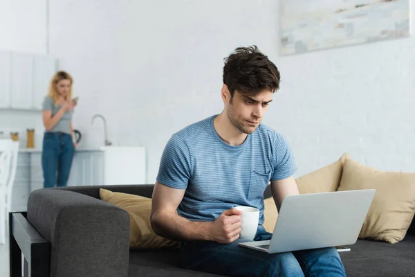 Enfoque Selectivo Del Hombre Guapo Mirando Ordenador Portátil Sosteniendo Taza — Foto de Stock