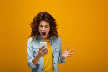 akıllı telefon bakarken ve turuncu çığlık redhead kadın gesturing 