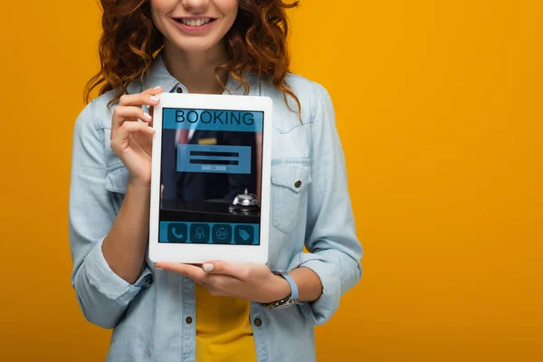 주황색으로 화면에 앱으로 디지털 태블릿을 들고있는 쾌활한 소녀의 — 스톡 사진
