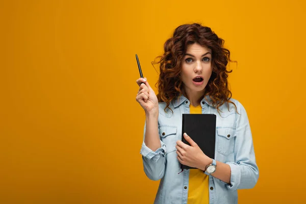 Surprised Redhead Girl Holding Notebook Pen Looking Camera Orange — Stock Photo, Image