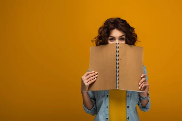 Young Curly Redhead Woman Covering Face Notebook Orange — Stock Photo, Image