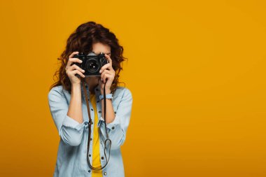 turuncu izole dijital kamera ile yüz kapsayan kıvırcık redhead fotoğrafçı 