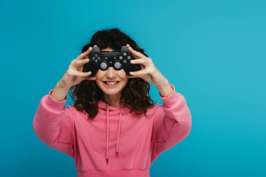 neşeli kıvırcık kızıl saçlı kız mavi joystick ile yüz kapsayan