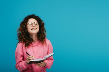 mavi izole defter ve kalem tutan gözlük mutlu kıvırcık kız