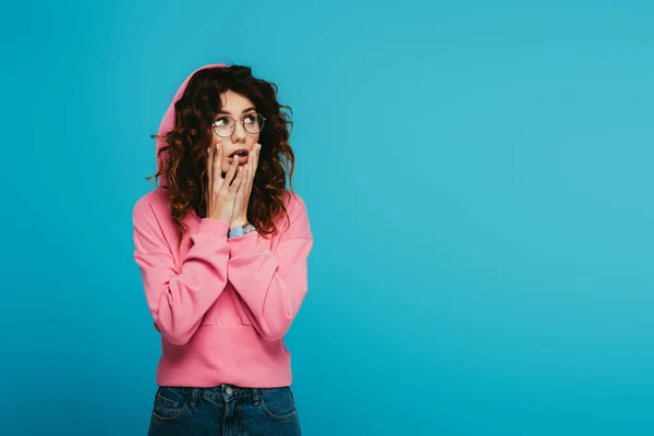 Verbaasd Redhead Meisje Aanraken Gezicht Terwijl Staande Blauw — Stockfoto