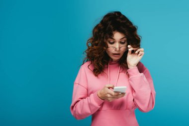 mavi akıllı telefon bakarak gözlük çekici kıvırcık kız