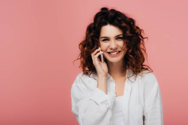 neşeli kıvırcık kız akıllı telefon konuşuyor ve pembe üzerinde gülümseyen