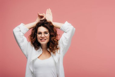 pembe üzerinde gesturing sırasında gözlük gülümseyen çekici kıvırcık kadın