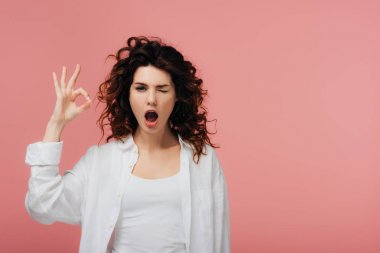 kırmızı saçlı kıvırcık genç kadın pembe izole ok işareti gösteren