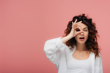 pembe ok işareti gösteren kırmızı saçlı kıvırcık genç kadın